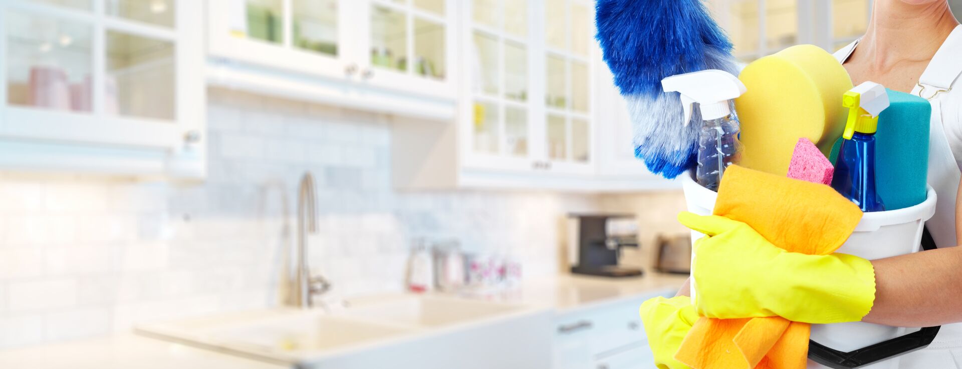 Professional cleaner with supplies in a bright, spotless kitchen